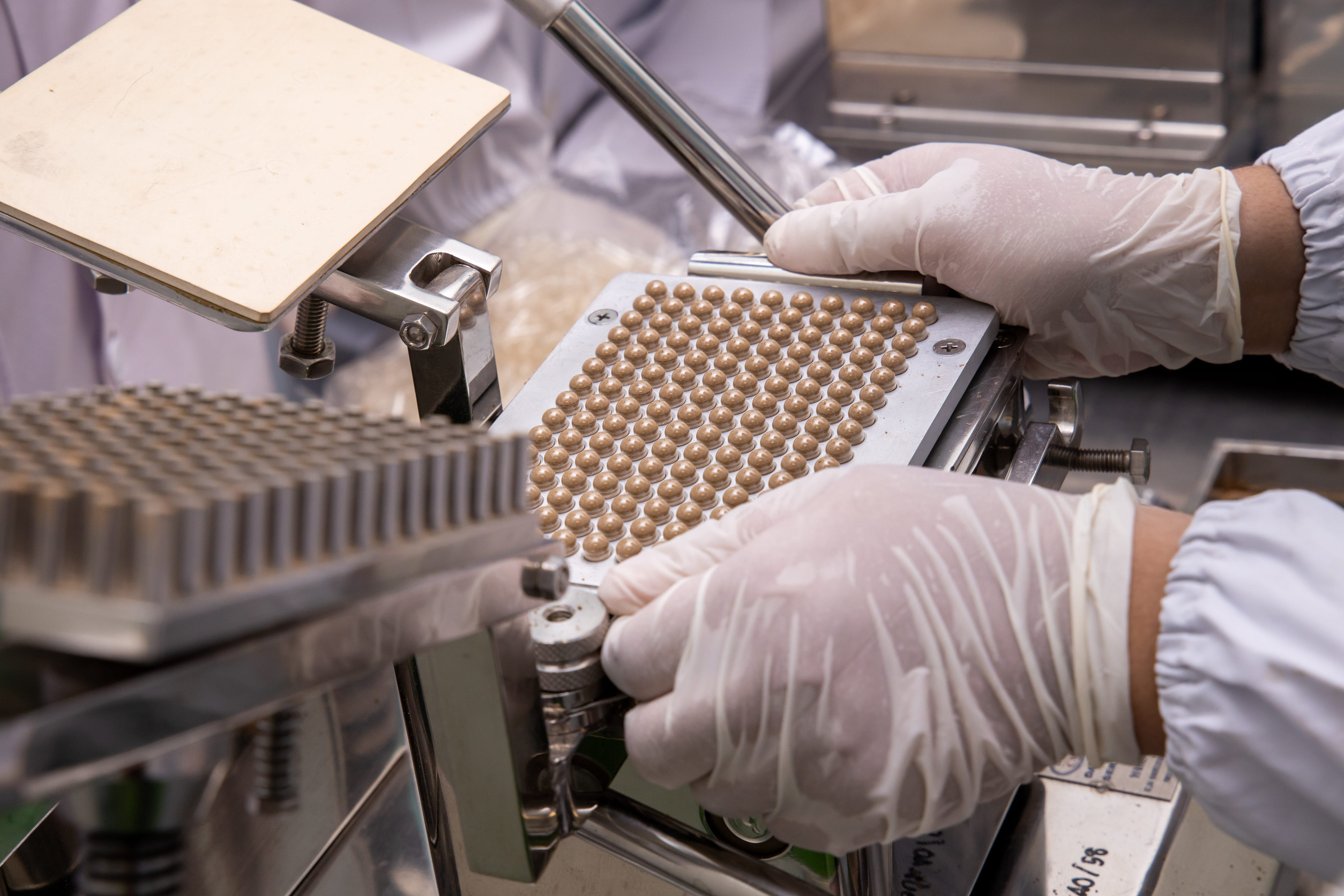 Hands filling pill packaging trays for organized medication packs